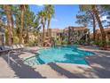Community pool area with lush landscaping, waterfall feature, lounge chairs and covered tables at 7950 W Flamingo Rd # 1003, Las Vegas, NV 89147