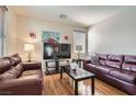 Comfortable living room with two leather sofas, wood flooring, and a large television at 987 Wembly Hills Pl, Henderson, NV 89011