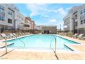 Stunning community pool with lounge chairs and umbrellas surrounded by modern residential buildings and sunny skies at 2501 Indigo Mountain St, Henderson, NV 89044