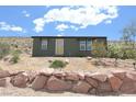 Exterior view of a modern home featuring desert landscaping, surrounded by natural beauty and native plants at 275 Vegas Dr, Goodsprings, NV 89019