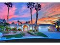 Single-story home with brick accents, arched windows, front yard, and brick steps with palm trees at sunset at 4418 Desert Bloom Ct, Las Vegas, NV 89129