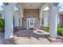 Close up of the front door with glass detailing, brick facade, pillars, and arched windows at 4418 Desert Bloom Ct, Las Vegas, NV 89129