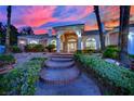 Charming single-story home with manicured landscaping, brick accents, and a welcoming entrance with brick steps at sunset at 4418 Desert Bloom Ct, Las Vegas, NV 89129
