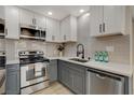 Modern kitchen with stainless steel appliances, gray subway tile backsplash, and two-tone cabinets at 5020 Village Dr, Las Vegas, NV 89142