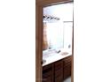 Bathroom featuring wood cabinets, broad mirror, and modern lighting at 671 Bourbon St, Pahrump, NV 89048