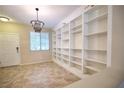 The living room showcases tile floors, a modern chandelier, a bright window and built-in bookshelves at 10449 Yew Blossom Ave, Las Vegas, NV 89166