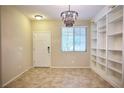 The living room showcases tile floors, a modern chandelier, a bright window and built-in bookshelves at 10449 Yew Blossom Ave, Las Vegas, NV 89166