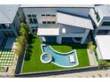 Aerial view of a home featuring a modern pool, swim up bar, jacuzzi and well-manicured lawn at 10748 Steel Ridge Ct, Las Vegas, NV 89135