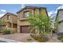 Charming home featuring a two-car garage, complemented by desert landscaping and a brick driveway at 10974 Cheshire Woods Ave, Las Vegas, NV 89166