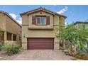 Charming home featuring a two-car garage, complemented by desert landscaping and a brick driveway at 10974 Cheshire Woods Ave, Las Vegas, NV 89166