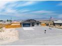 A single-Gathering home boasting gravel landscaping, a two-car garage, and a flagpole, offering a serene living environment at 1500 E Laguna St, Pahrump, NV 89048