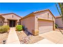 Tan home featuring a two-car garage, desert landscaping, and a walkway leading to the front door at 2106 King Mesa Dr, Henderson, NV 89012