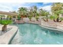 Backyard pool featuring a stone waterfall, lush tropical plants, and a shaded patio at 2168 Big Bar Dr, Henderson, NV 89052