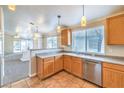 Bright kitchen with stainless steel dishwasher, wooden cabinets, and a view into the living area at 2177 Hidden Ranch Ter, Henderson, NV 89052