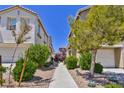 View of landscaped walkway between two-story townhouses, showcasing curb appeal and community design at 23 Hudson Canyon St # 3, Henderson, NV 89012