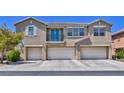 Exterior view of a three-story townhouse featuring a small balcony and a trio of garages in a contemporary style at 23 Hudson Canyon St # 3, Henderson, NV 89012