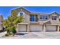 Exterior view of a three-story townhouse featuring a small balcony and a trio of garages in a contemporary style at 23 Hudson Canyon St # 3, Henderson, NV 89012