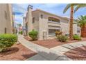 Low-rise condo building with blue railings, mature palm trees, and sidewalks on a sunny day, featuring well-kept landscaping at 2725 S Nellis Blvd # 2168, Las Vegas, NV 89121
