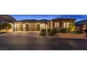 Beautiful home exterior with a three-car garage, lush landscaping, and well-maintained curb appeal at twilight at 6192 Lautman Ridge Ct, Las Vegas, NV 89141
