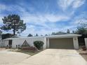 Neutral home featuring two-car garage, decorative yard art and desert landscaping in a sunny setting at 6215 Darby Ave, Las Vegas, NV 89146