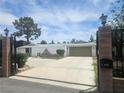 Single story home featuring neutral exterior, desert landscaping and a two car garage behind a gated entry at 6215 Darby Ave, Las Vegas, NV 89146