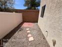 Enclosed backyard with a rock garden area and stepping stones to a small brick patio at 7249 Linaria Rd, Las Vegas, NV 89113
