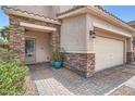 Inviting home entrance featuring stone accents, a paver walkway, and a two-car garage at 9853 Bangalore Ct, Las Vegas, NV 89148