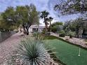Lush backyard showcasing artificial turf, mature trees, and a serene putting green for outdoor recreation at 10248 Maggira Pl, Las Vegas, NV 89135