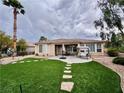 Well-maintained backyard featuring artificial grass, a paved patio, and mature landscaping at 10248 Maggira Pl, Las Vegas, NV 89135