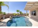 Beautiful pool with a waterfall feature, surrounded by landscaping and a covered patio area at 2221 River Grove Dr, Henderson, NV 89044
