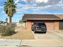 House exterior with a brown two car garage, desert landscaping, and a parked car in the driveway at 3936 Rive Gauche St, Las Vegas, NV 89115