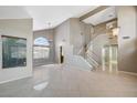 Open-concept living room with tile floors, a staircase, and ample natural light from the large windows at 5609 Indian Ridge Dr, North Las Vegas, NV 89031