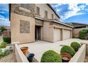 A tan two story house with a three car garage shows manicured landscaping and a well kept driveway at 741 Flowing Meadow Dr, Henderson, NV 89014