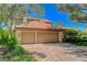 Spacious three-car garage with a brick driveway, complemented by mature trees and landscaping at 7988 Pinnacle Peak Ave, Las Vegas, NV 89113