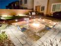Inviting backyard with paver patio, fire pit, outdoor seating, and tasteful landscape lighting at 9934 Iron Creek Ave, Las Vegas, NV 89178