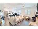 Bright and airy living room with hardwood floors, ceiling fan, and comfortable sectional sofa at 9934 Iron Creek Ave, Las Vegas, NV 89178