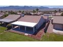Aerial view of backyard featuring covered patio with ceiling fans and well-maintained lawn at 1195 Golf Club Dr, Laughlin, NV 89029
