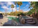Sparkling pool and spa surrounded by lush greenery and palm trees in a serene backyard setting at 340 Autumn Palace Ct, Las Vegas, NV 89144