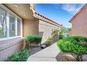 Landscaped walkway, with bright green bushes, leading to a home's side entrance and window at 5008 Shoal Creek Cir, Las Vegas, NV 89113