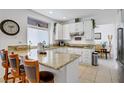 Bright kitchen featuring white cabinets, granite countertops, tile flooring, and a breakfast bar at 7621 Hackensack Ct, Las Vegas, NV 89128