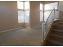 Bright living room featuring large windows, neutral carpet, and staircase at 9709 Port Orange Ln, Las Vegas, NV 89134