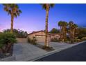 Home with a large driveway, three-car garage, desert landscaping, and mature palm trees at 10674 Chillingham Dr, Las Vegas, NV 89183