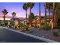 Attractive single-story home with desert landscaping, a courtyard, and exterior lighting at dusk at 10674 Chillingham Dr, Las Vegas, NV 89183