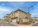 Side view of a tan two-story townhouse featuring an attached garage and manicured landscaping at 173 Petaluma Valley Dr, Las Vegas, NV 89138