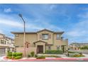 Exterior view of tan two-story townhouse with brick accents, attractive landscaping, and a red tile roof at 173 Petaluma Valley Dr, Las Vegas, NV 89138