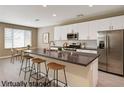 Contemporary kitchen boasts stainless steel appliances, sleek white cabinetry, and an island with barstool seating at 3760 Paseo De Paz Ave, Las Vegas, NV 89115