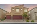 A two-story home with a neutral color scheme, a three car garage, desert landscaping and a brick driveway at 4039 Beech Fern Ave, North Las Vegas, NV 89084