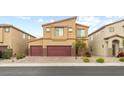 Tan two-story home with a three car garage, desert landscaping, and brick driveway at 4039 Beech Fern Ave, North Las Vegas, NV 89084