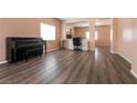 Spacious living room with dark wood-look flooring, large windows, and piano, offers flexibility and comfort at 5835 Running Horse Dr, North Las Vegas, NV 89081