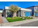 Modern home exterior with a well-maintained lawn, tidy landscaping, and a blue garage door at 7208 Grace Estate Ave, Las Vegas, NV 89113